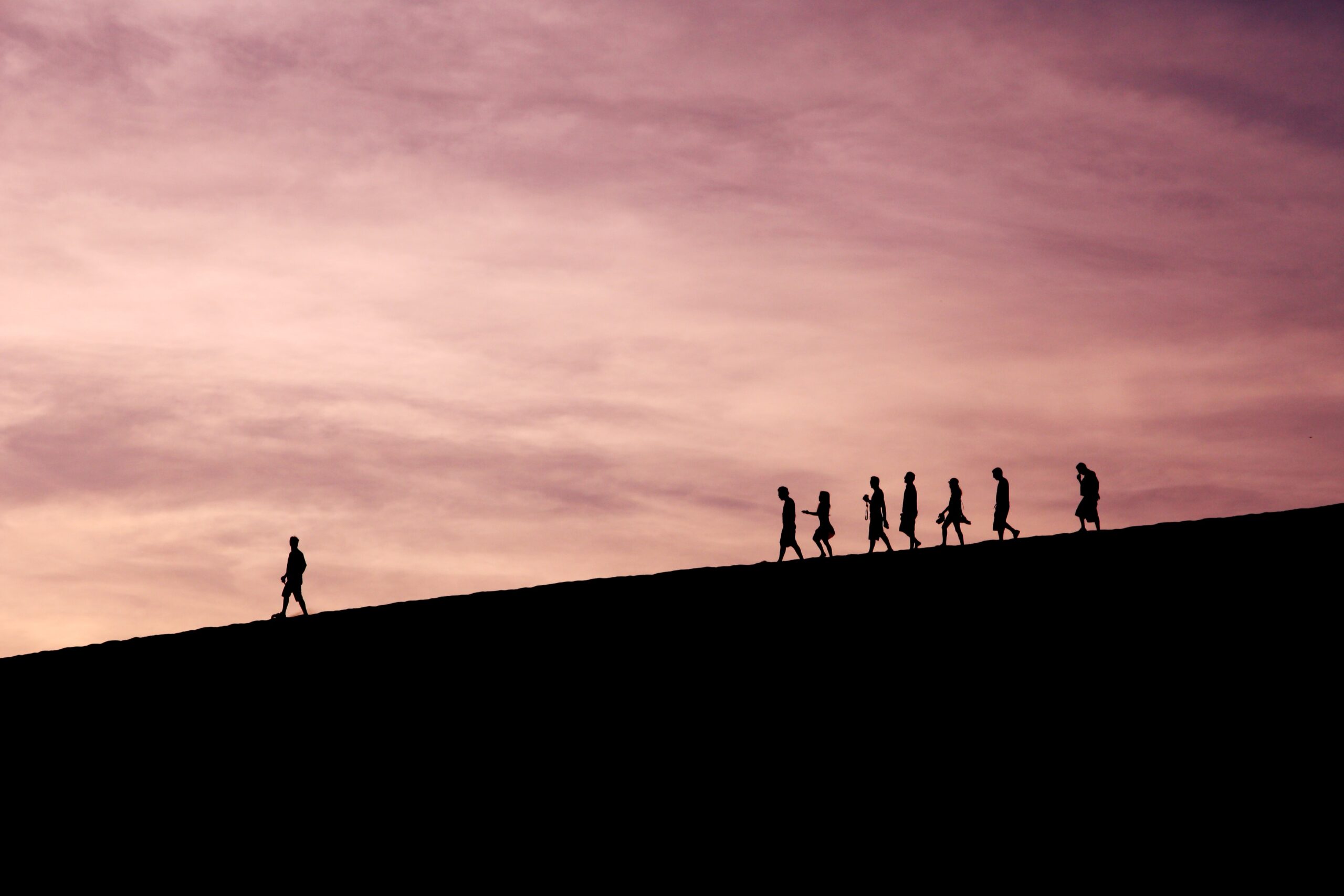 People walking down a hill in silhouette